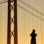 Silhouette of a person and a bridge against an golden sky