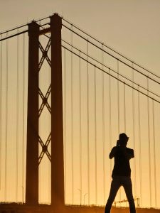Silhouette of a person and a bridge against an golden sky
