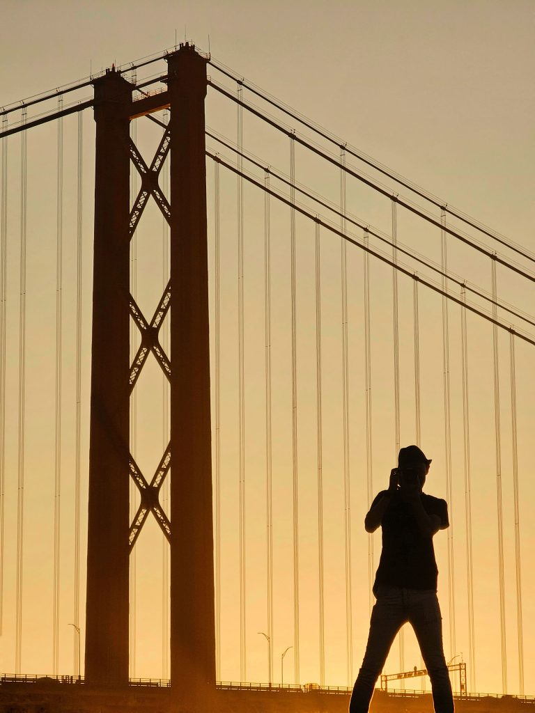 Silhouette of a person and a bridge against an golden sky