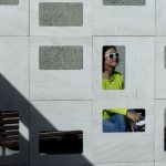 Woman in shades seen through holes in a wall