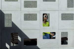 Woman in shades seen through holes in a wall