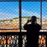Silhoutte of a person against the backdrop of Lisbon roofs seen through a grid
