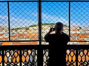 Silhoutte of a person against the backdrop of Lisbon roofs seen through a grid
