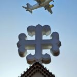 An Airplane flying over a cross
